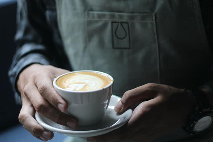 Konobar sa obe ruke drži šolju kafe